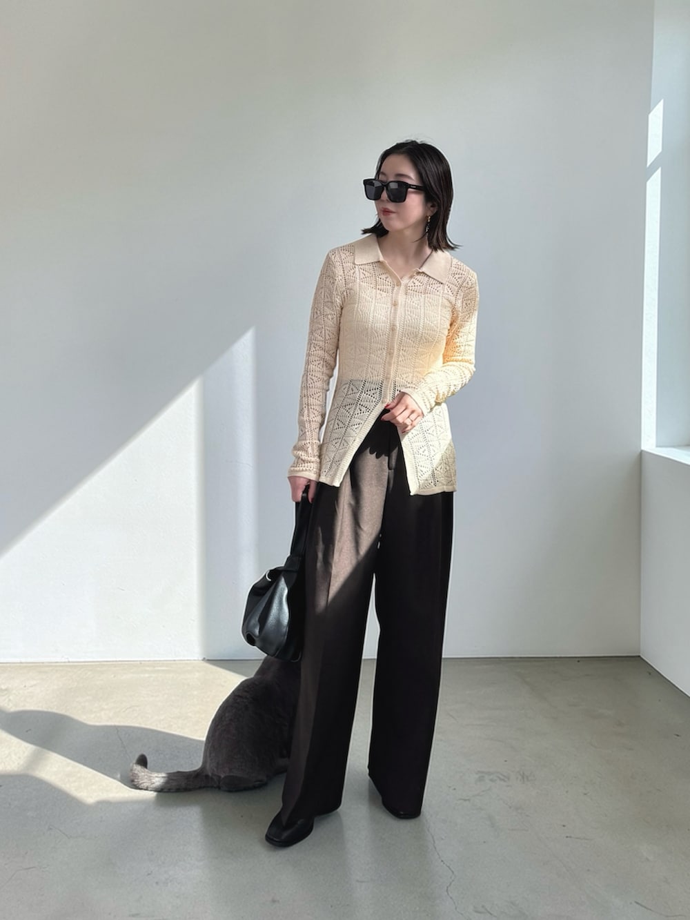 ブラウン系のその他パンツ、ホワイト系のニット/セーター、ブラック系のハンドバッグを着用したレディースの春コーディネートの3枚目の写真