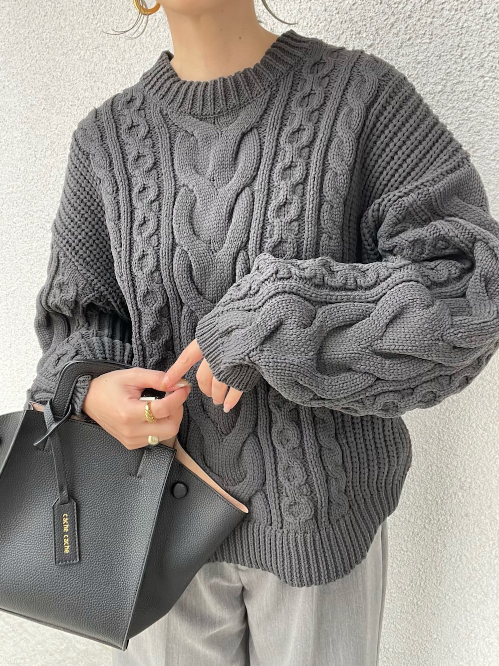 ブラック系のニット/セーター、ブラック系のハンドバッグを着用したレディースの秋コーディネートの5枚目の写真