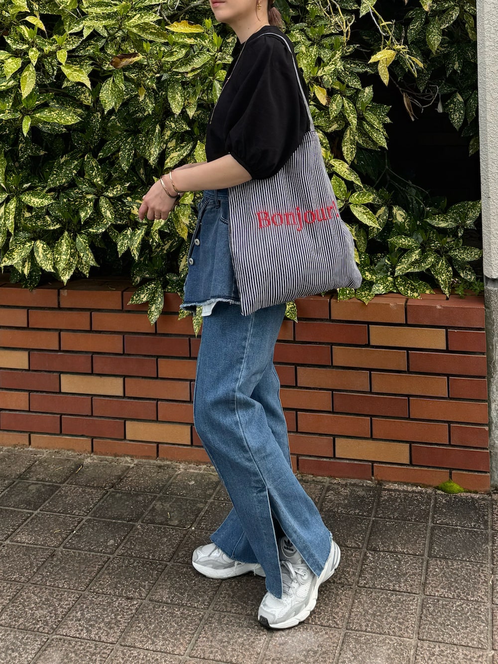 ブラック系のシャツ/ブラウス、ブラック系のトートバッグ、ブルー系のデニムパンツを着用したレディースの春コーディネートの4枚目の写真