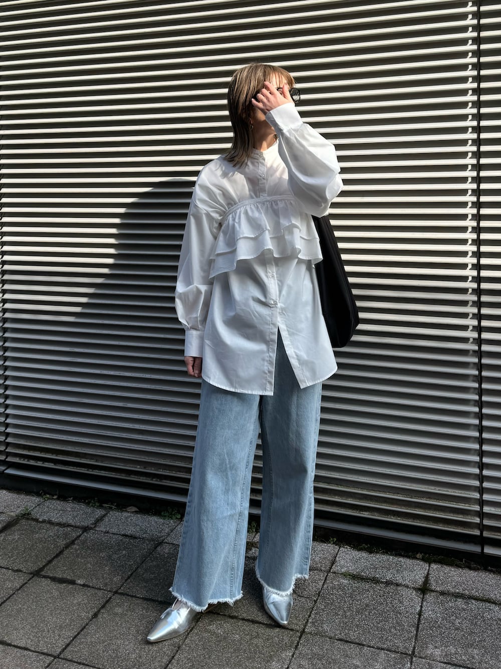 ホワイト系のシャツ/ブラウス、シルバー系のパンプス、ブルー系のデニムパンツを着用したレディースの冬コーディネートの4枚目の写真