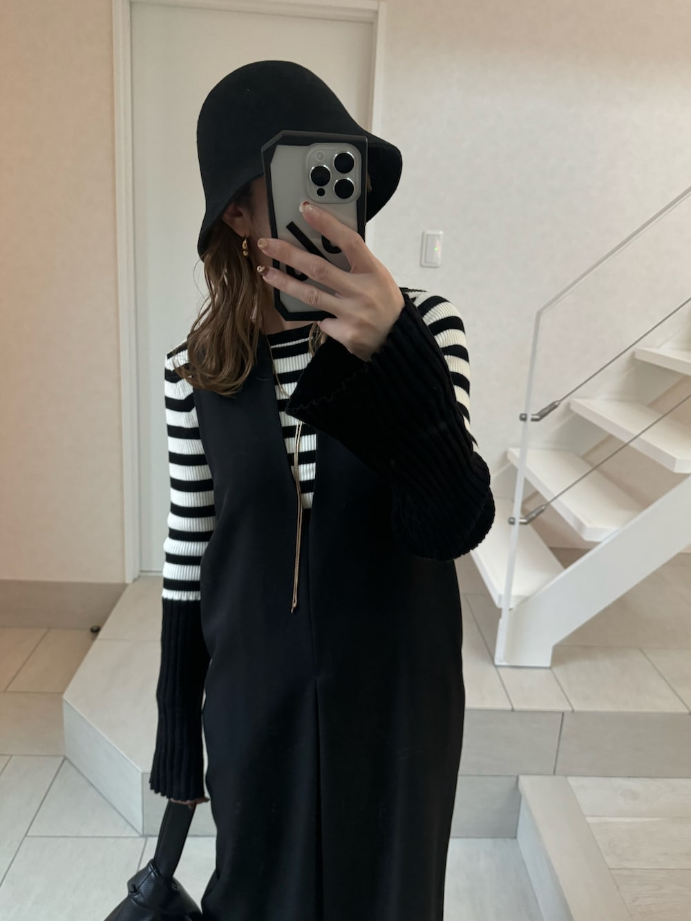 ブラック系のワンピース、ブラック系のハンドバッグ、ブラック系のニット/セーターを着用したレディースの冬コーディネートの2枚目の写真