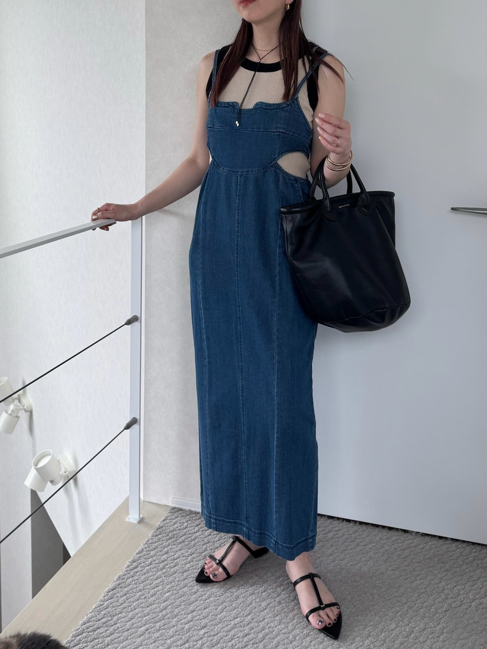 ブラック系のトートバッグ、ブルー系のジャンパースカート、ブラック系のサンダルを着用したレディースの夏コーディネートの3枚目の写真