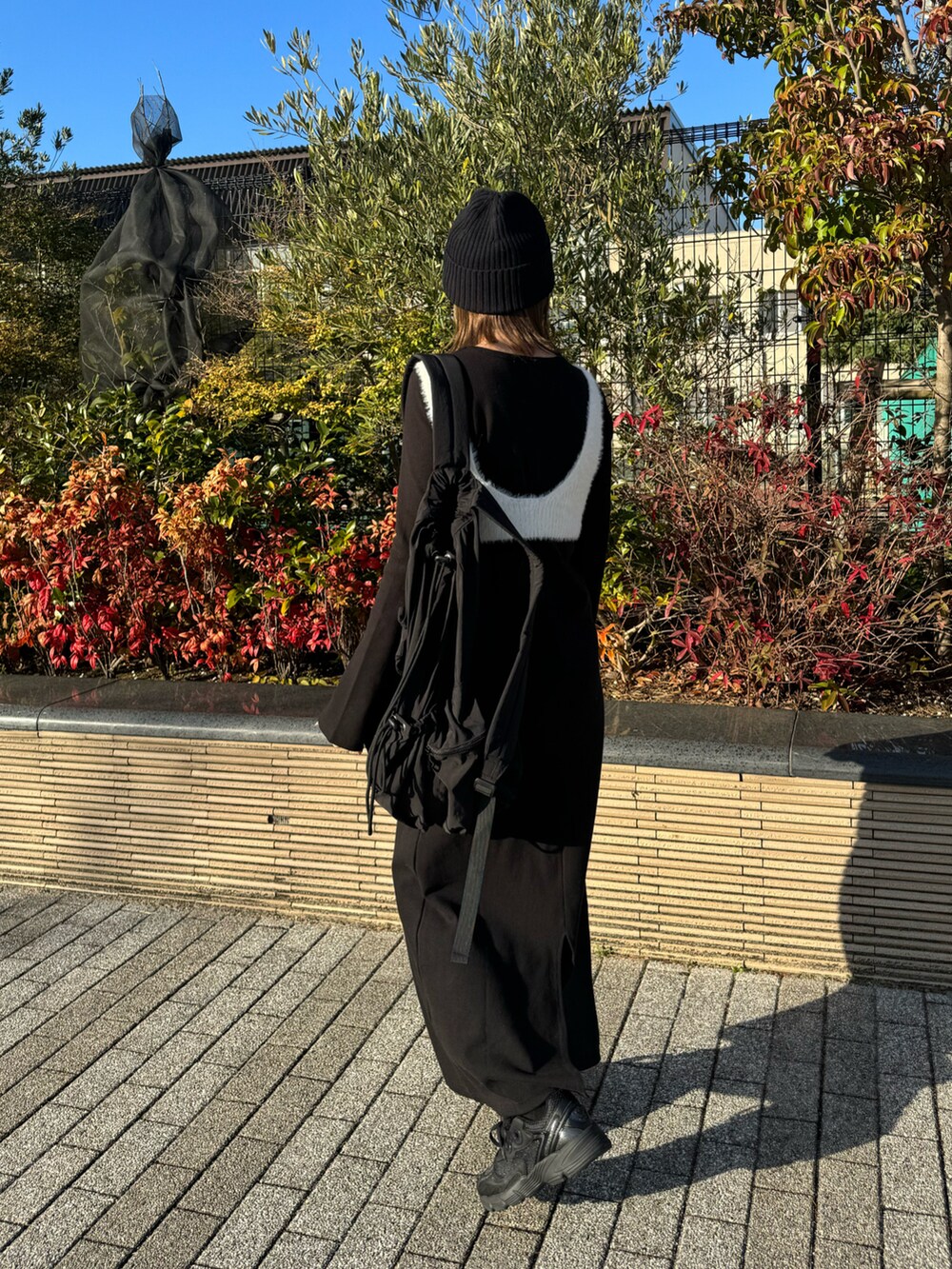 ホワイト系のニット/セーター、ブラック系のワンピース、ブラック系のスニーカーを着用したレディースの冬コーディネートの5枚目の写真