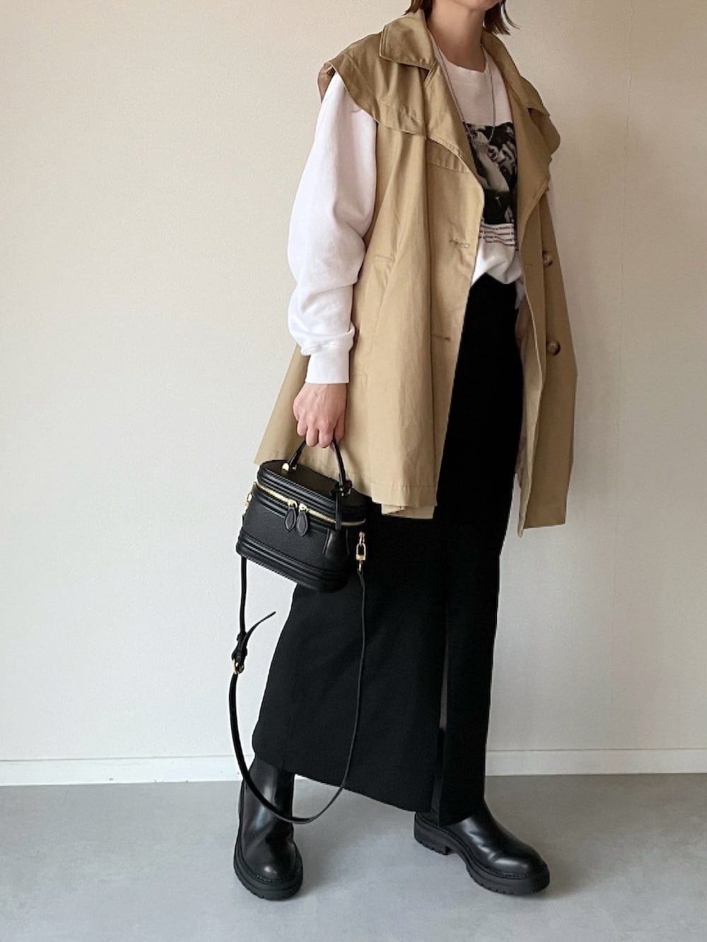 ホワイト系のスウェット、イエロー系のトレンチコート、ブラック系のブーツを着用したレディースの冬コーディネートの2枚目の写真