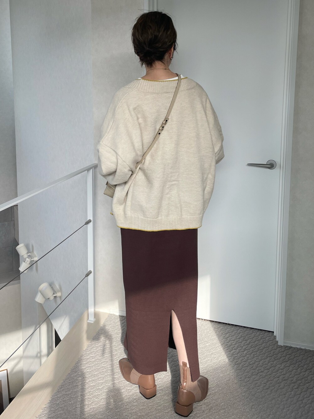 ホワイト系のカーディガン/ボレロ、ブラウン系のスカート、ブラウン系のブーツを着用したレディースの冬コーディネートの4枚目の写真