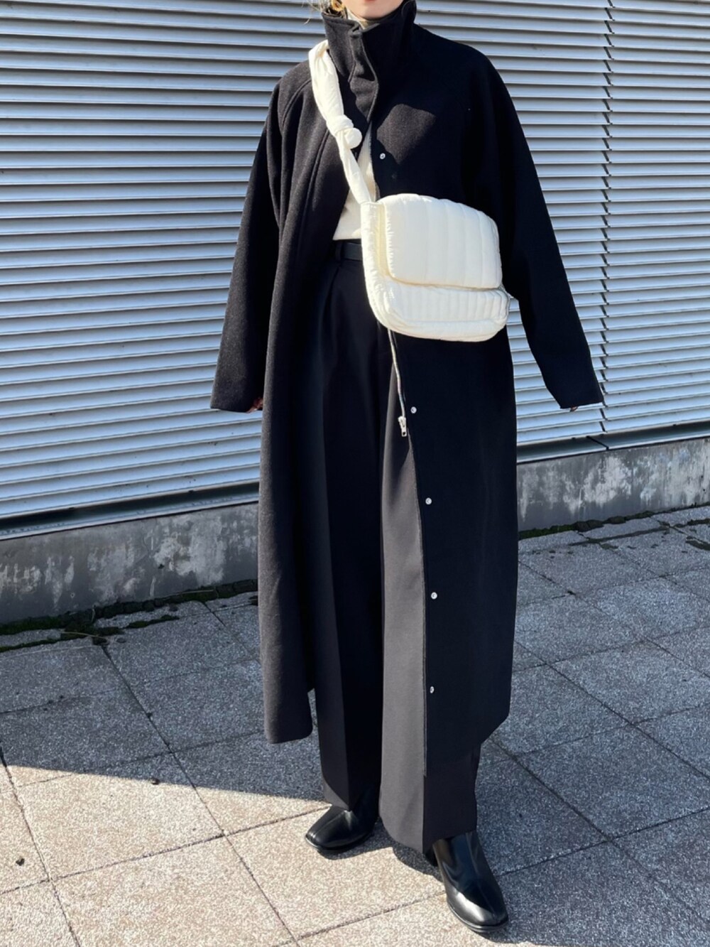 ブラック系のその他アウター、ホワイト系のニット/セーター、ブラック系のその他パンツを着用したレディースの秋コーディネートの3枚目の写真