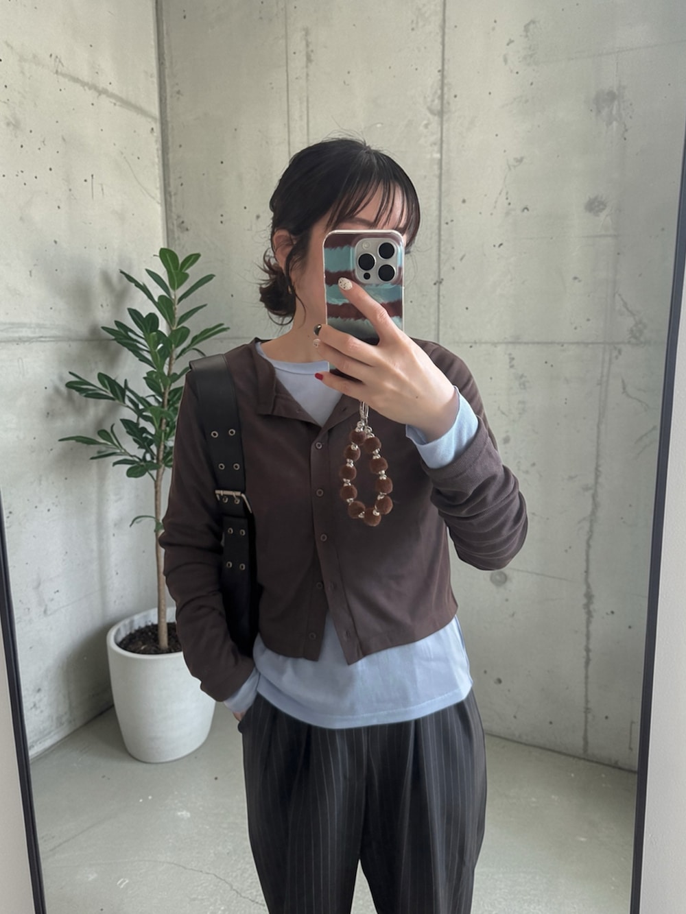 ブラウン系のカーディガン/ボレロ、グレー系のスラックス、ブラック系のハンドバッグを着用したレディースの春コーディネートの5枚目の写真