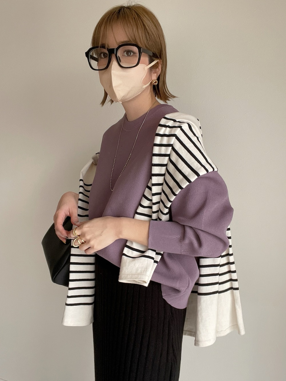 パープル系のニット/セーター、ブラック系のスカート、ブラック系のボストンバッグを着用したレディースの春コーディネートの2枚目の写真