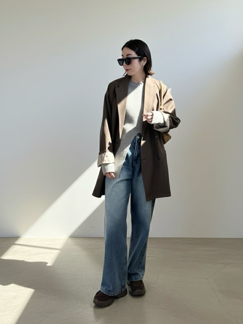 グレー系のニット/セーター、ブラウン系のテーラードジャケット、ブルー系のデニムパンツを着用したレディースの冬コーディネートの2枚目の写真