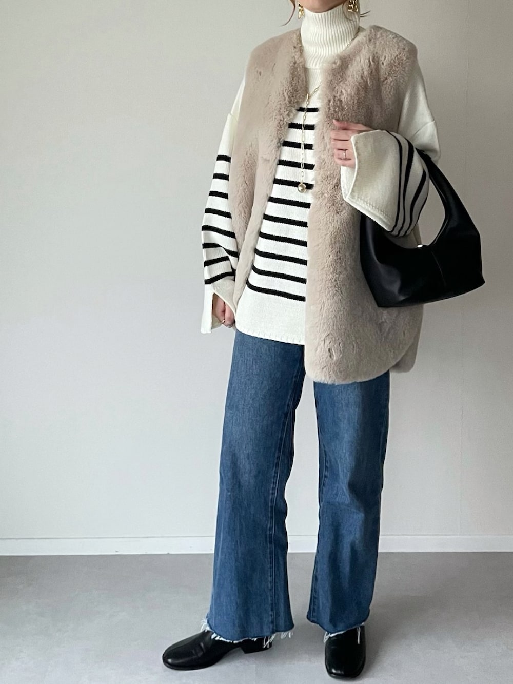 ホワイト系のニット/セーター、ブルー系のデニムパンツ、ブラック系のその他シューズを着用したレディースの冬コーディネートの2枚目の写真