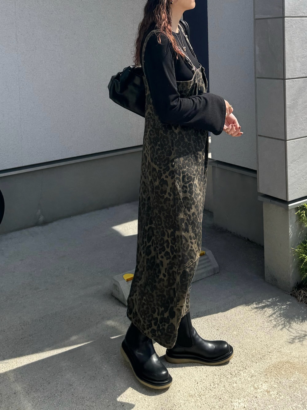 ブラック系のボストンバッグ、ブラック系のブーツ、ブラウン系のキャップを着用したレディースの秋コーディネートの4枚目の写真