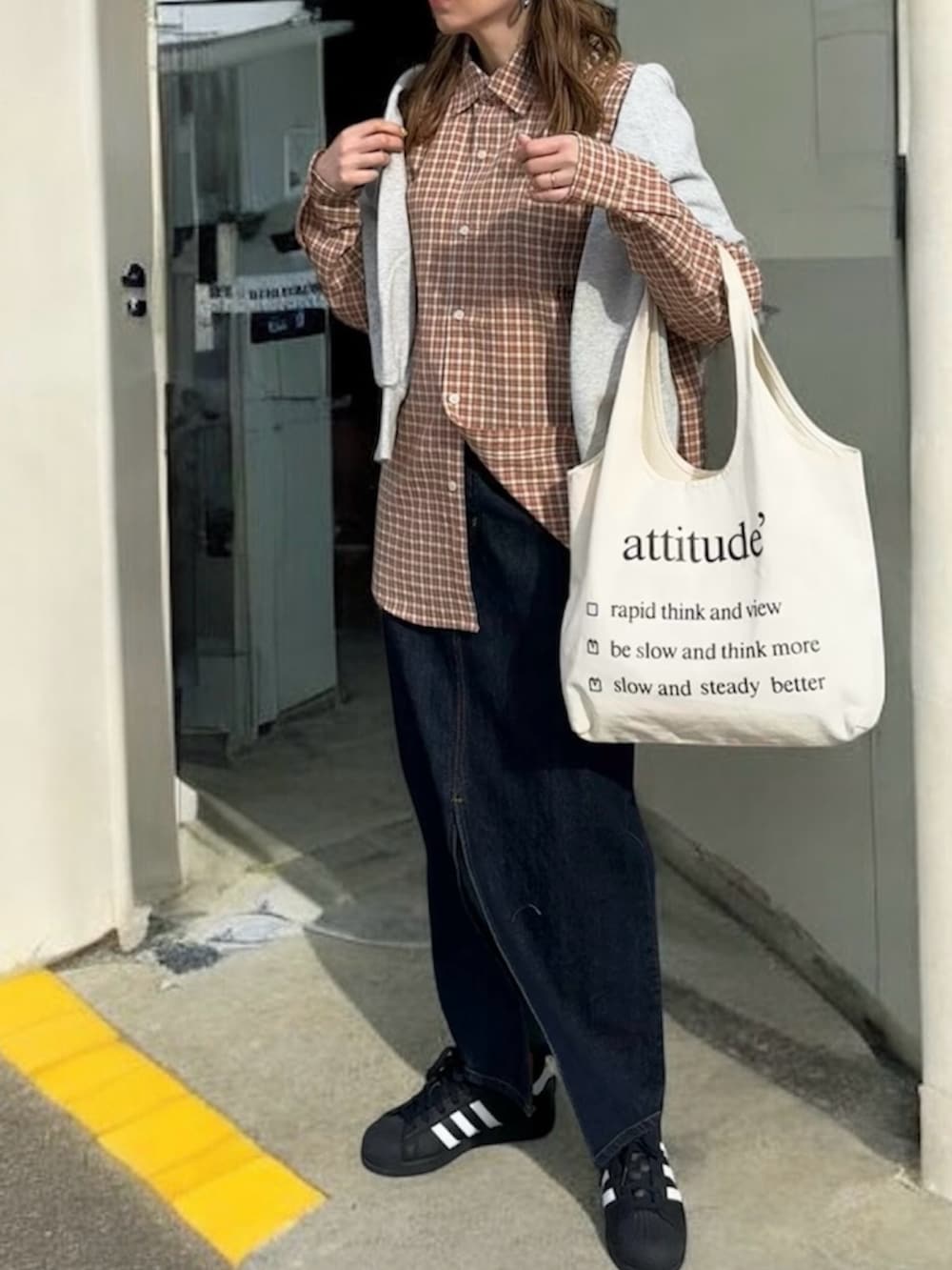 ブラウン系のシャツ/ブラウス、ブルー系のデニムスカート、ブラック系のスニーカーを着用したレディースの春コーディネートの2枚目の写真