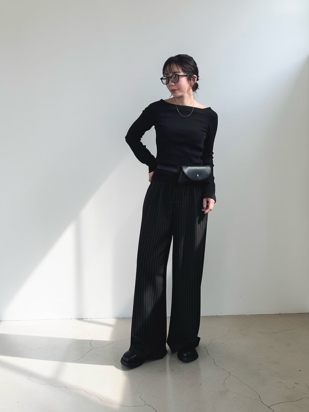 ブラック系のボディバッグ/ウエストポーチ、ブラック系のTシャツ/カットソー、ブラック系のスラックスを着用したレディースの春コーディネートの2枚目の写真