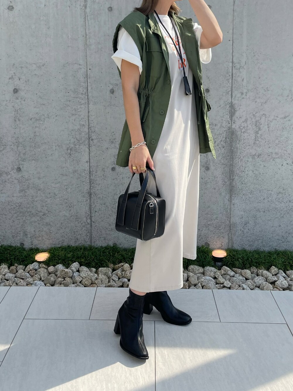 ブラック系のブーツ、ベージュ系のジャンパースカート、ブラック系のボストンバッグを着用したレディースの秋コーディネートの4枚目の写真