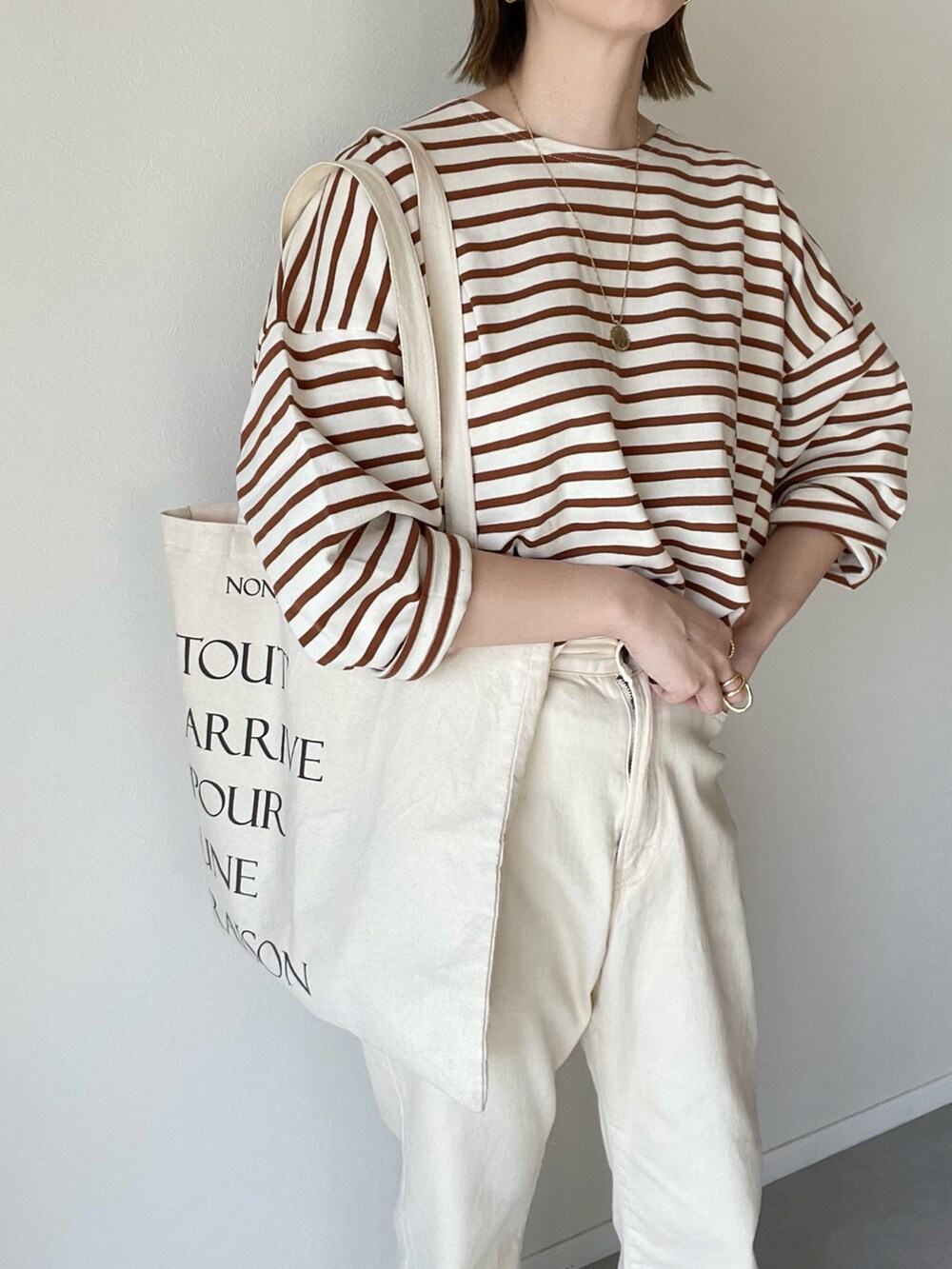 ベージュ系のTシャツ/カットソー、ホワイト系のデニムパンツを着用したレディースの春コーディネートの4枚目の写真