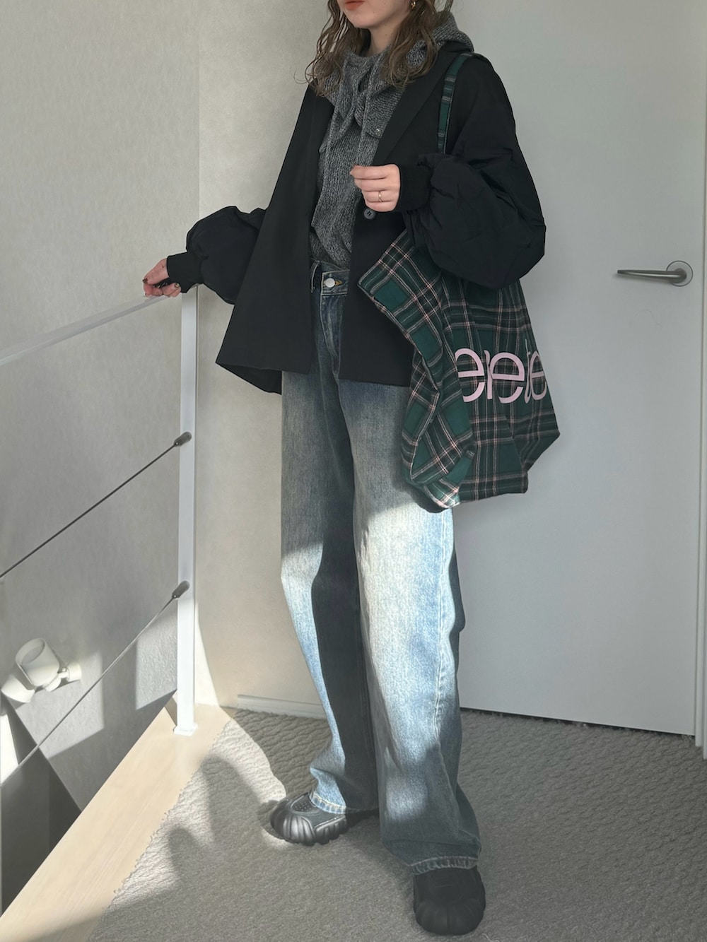 グレー系のニット/セーター、グリーン系のトートバッグ、ブルー系のデニムパンツを着用したレディースの冬コーディネートの2枚目の写真