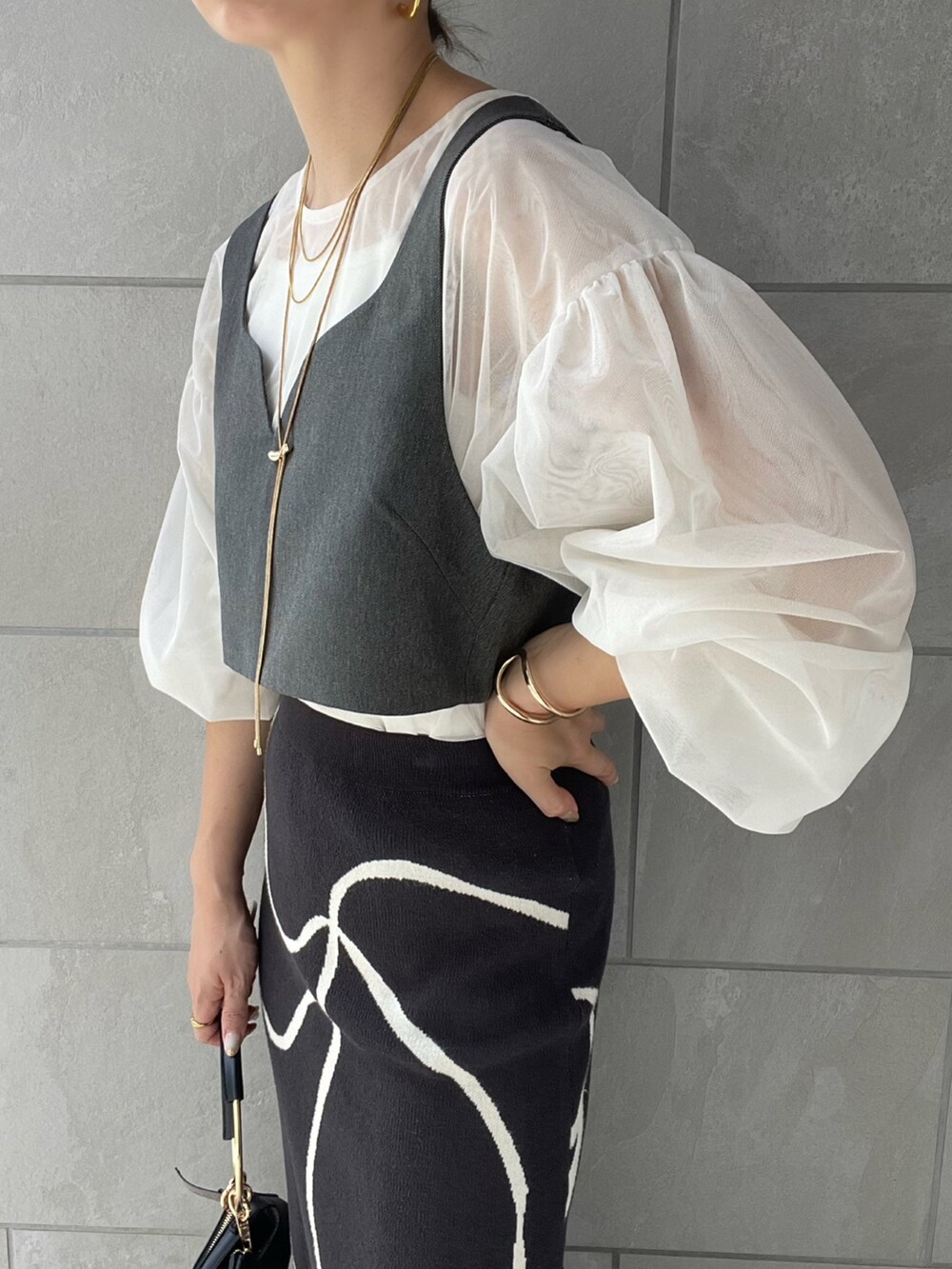 グレー系のスカート、ホワイト系のシャツ/ブラウス、ブラック系のハンドバッグを着用したレディースの夏コーディネートの3枚目の写真