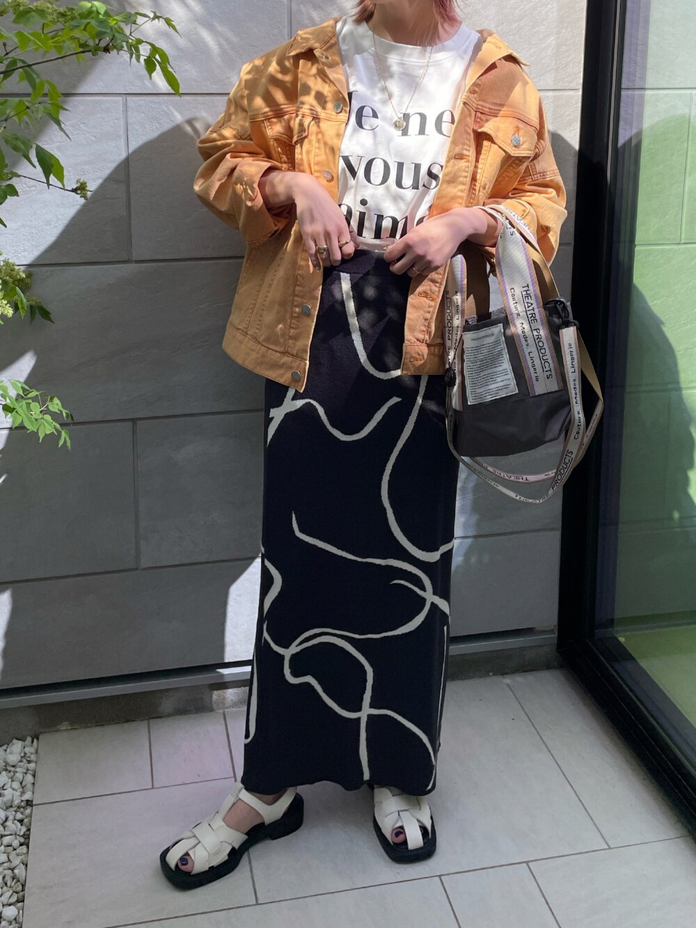 ホワイト系のTシャツ/カットソー、ホワイト系のサンダル、グレー系のスカートを着用したレディースの春コーディネートの2枚目の写真