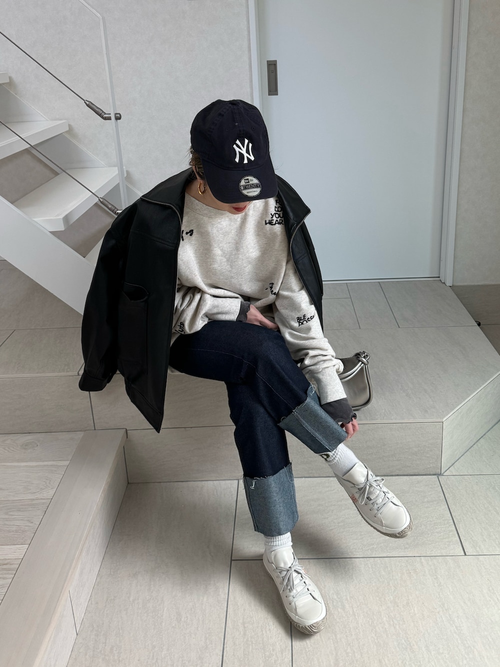 ホワイト系のスウェット、シルバー系のショルダーバッグ、ブラック系のライダースジャケットを着用したレディースの冬コーディネートの3枚目の写真