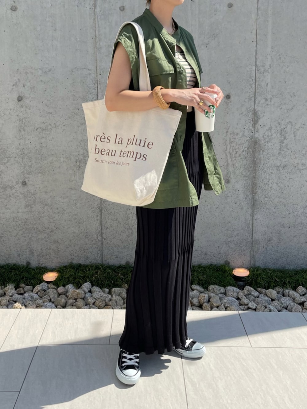 ブラック系のスカート、グリーン系のベスト、ベージュ系のキャミソールを着用したレディースの夏コーディネートの2枚目の写真