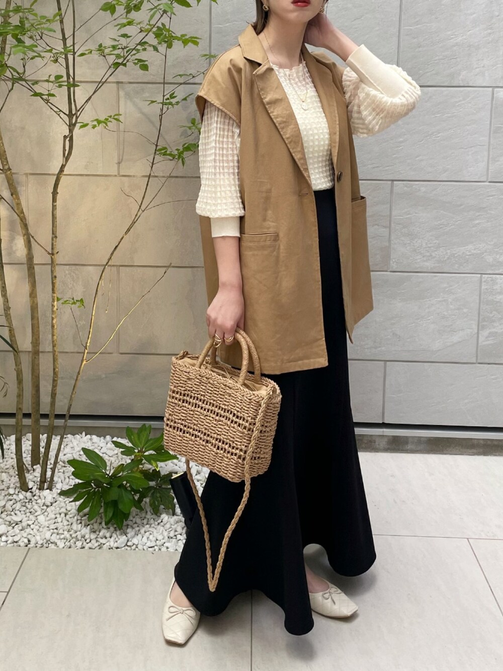 イエロー系のベスト、ホワイト系のニット/セーター、ホワイト系のパンプスを着用したレディースの春コーディネートの3枚目の写真