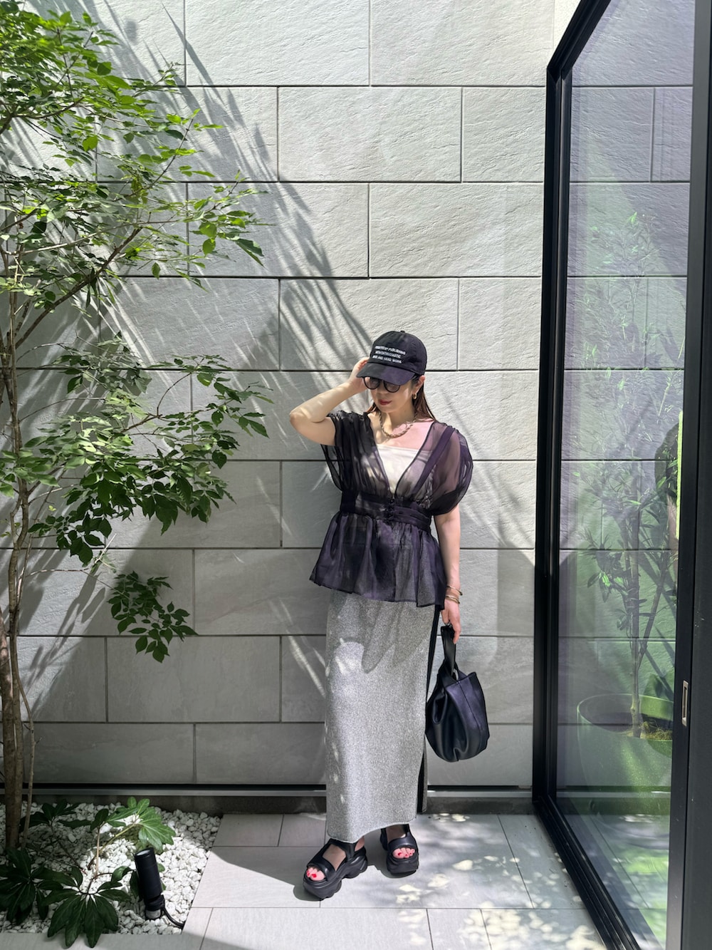 ブラック系のTシャツ/カットソー、ブラック系のサンダル、ブラック系のハンドバッグを着用したレディースの夏コーディネートの3枚目の写真