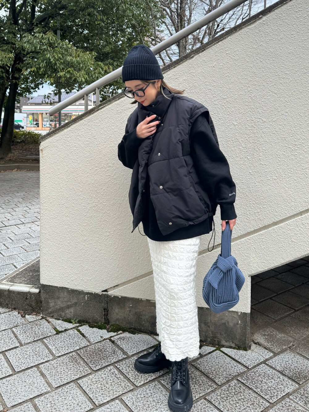 ブラック系のスウェット、ブラック系のブーツ、ブルー系のハンドバッグを着用したレディースの冬コーディネートの2枚目の写真