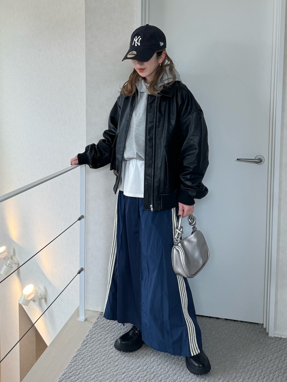 ブラック系のブルゾン、シルバー系のショルダーバッグ、ブルー系のスカートを着用したレディースの冬コーディネートの3枚目の写真