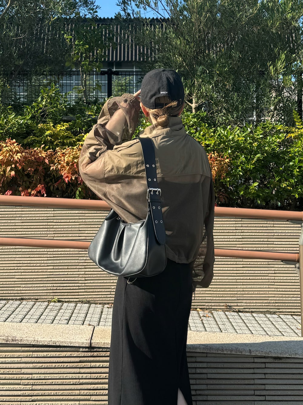 レッド系のスニーカー、ブラック系のハンドバッグ、ブラック系のワンピースを着用したレディースの秋コーディネートの4枚目の写真