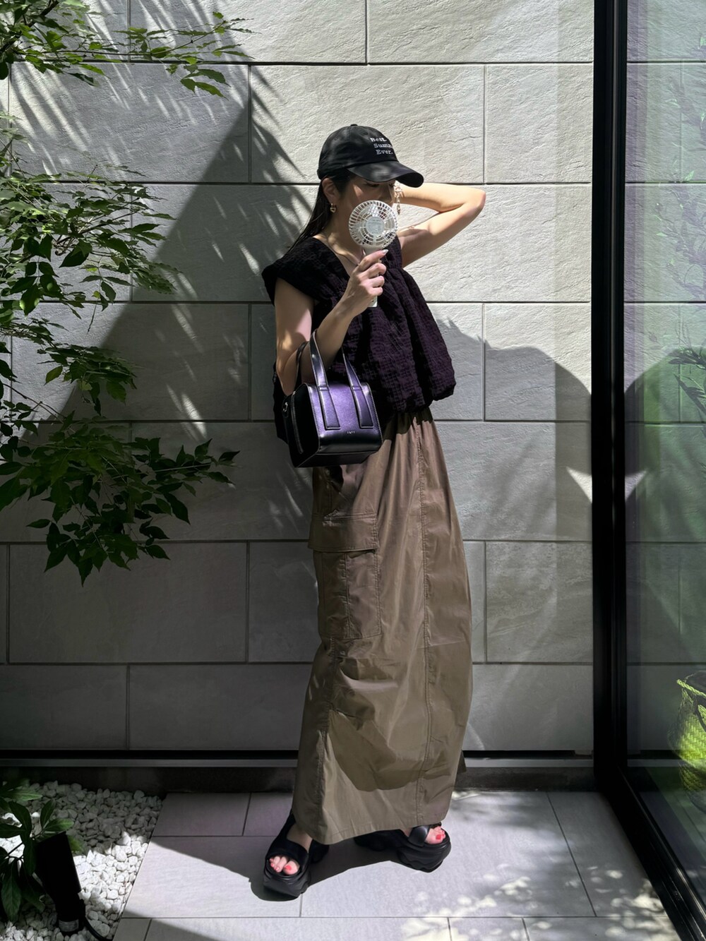 ブラック系のその他トップス、グリーン系のスカート、ブラック系のサンダルを着用したレディースの夏コーディネートの2枚目の写真