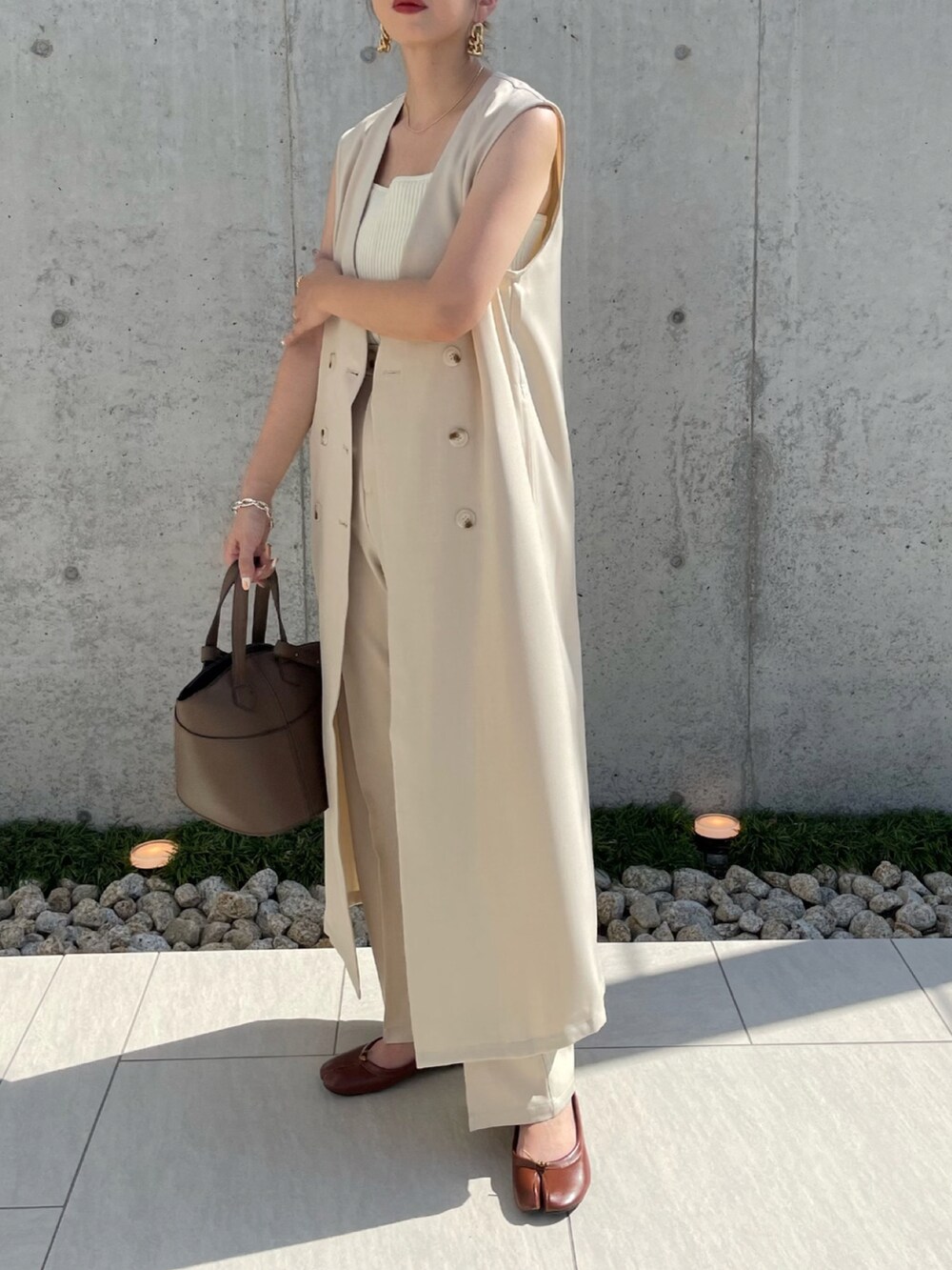 ブラウン系のショルダーバッグ、ブラウン系のパンプス、ホワイト系のキャミソールを着用したレディースの夏コーディネートの2枚目の写真