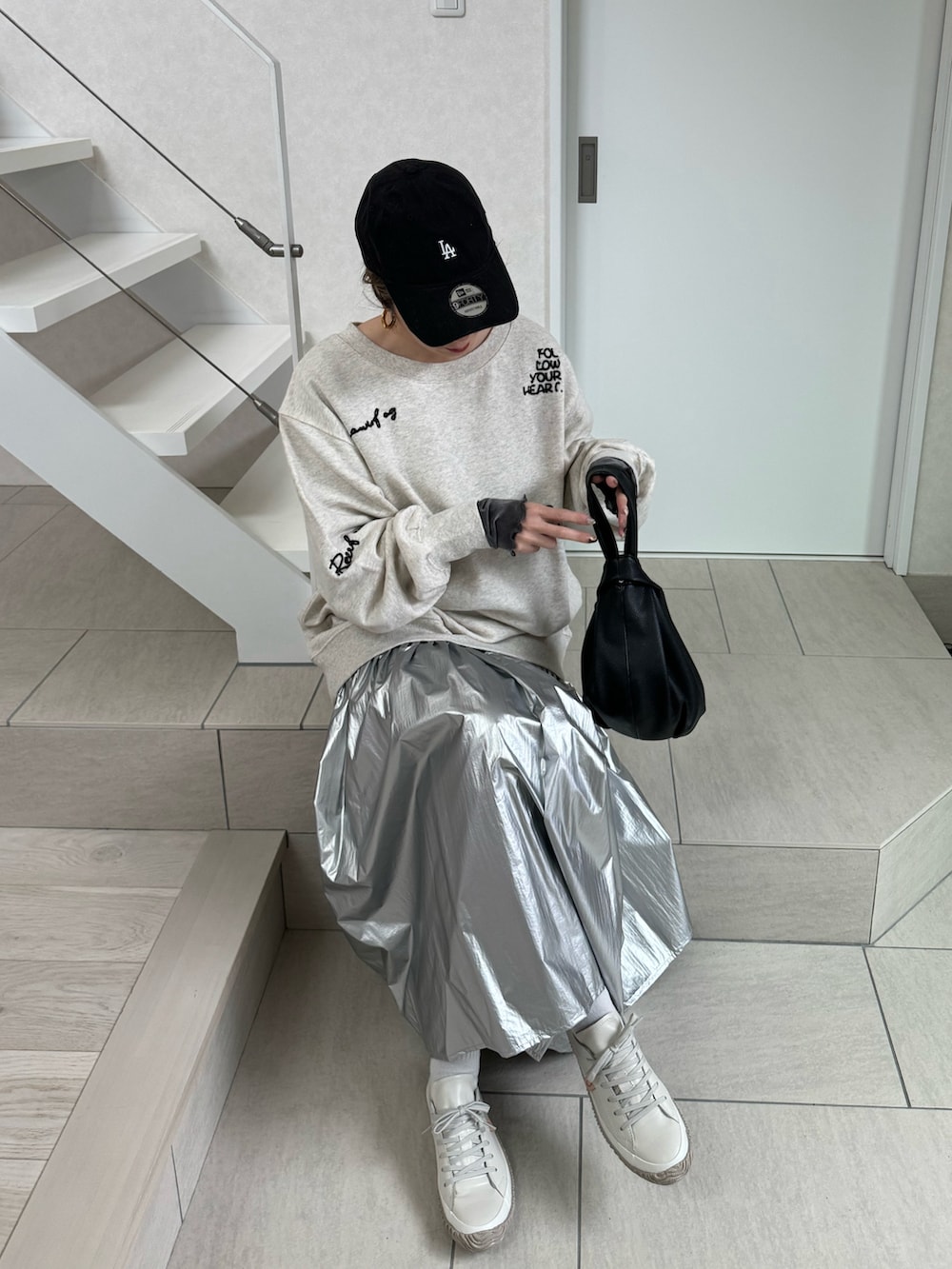 ホワイト系のスウェット、シルバー系のスカート、ブラック系のハンドバッグを着用したレディースの冬コーディネートの3枚目の写真