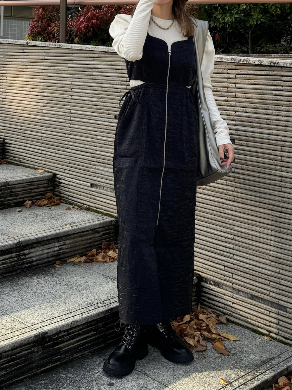 ブラック系のジャンパースカート、ホワイト系のTシャツ/カットソー、ブラック系のブーツを着用したレディースの秋コーディネートの2枚目の写真