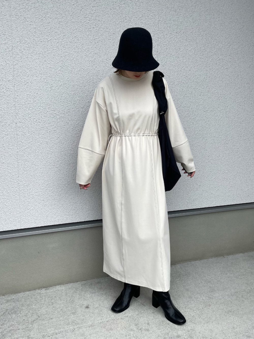 ホワイト系のワンピース、ブラック系のショルダーバッグ、ブラック系のブーツを着用したレディースの秋コーディネートの2枚目の写真