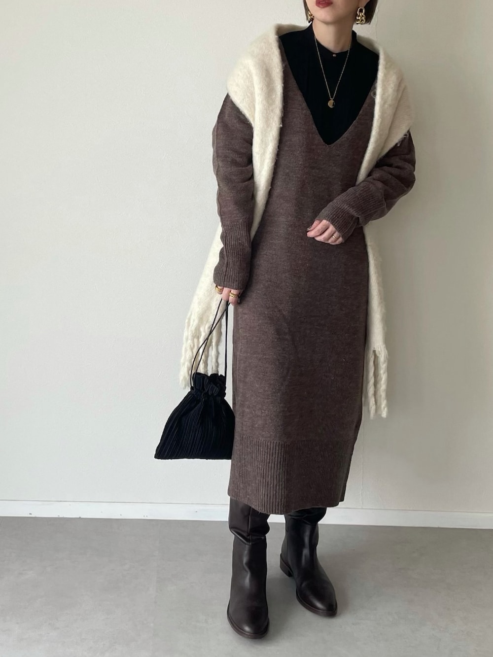 ブラウン系のワンピース、ブラック系のハンドバッグ、ブラウン系のブーツを着用したレディースの冬コーディネートの3枚目の写真