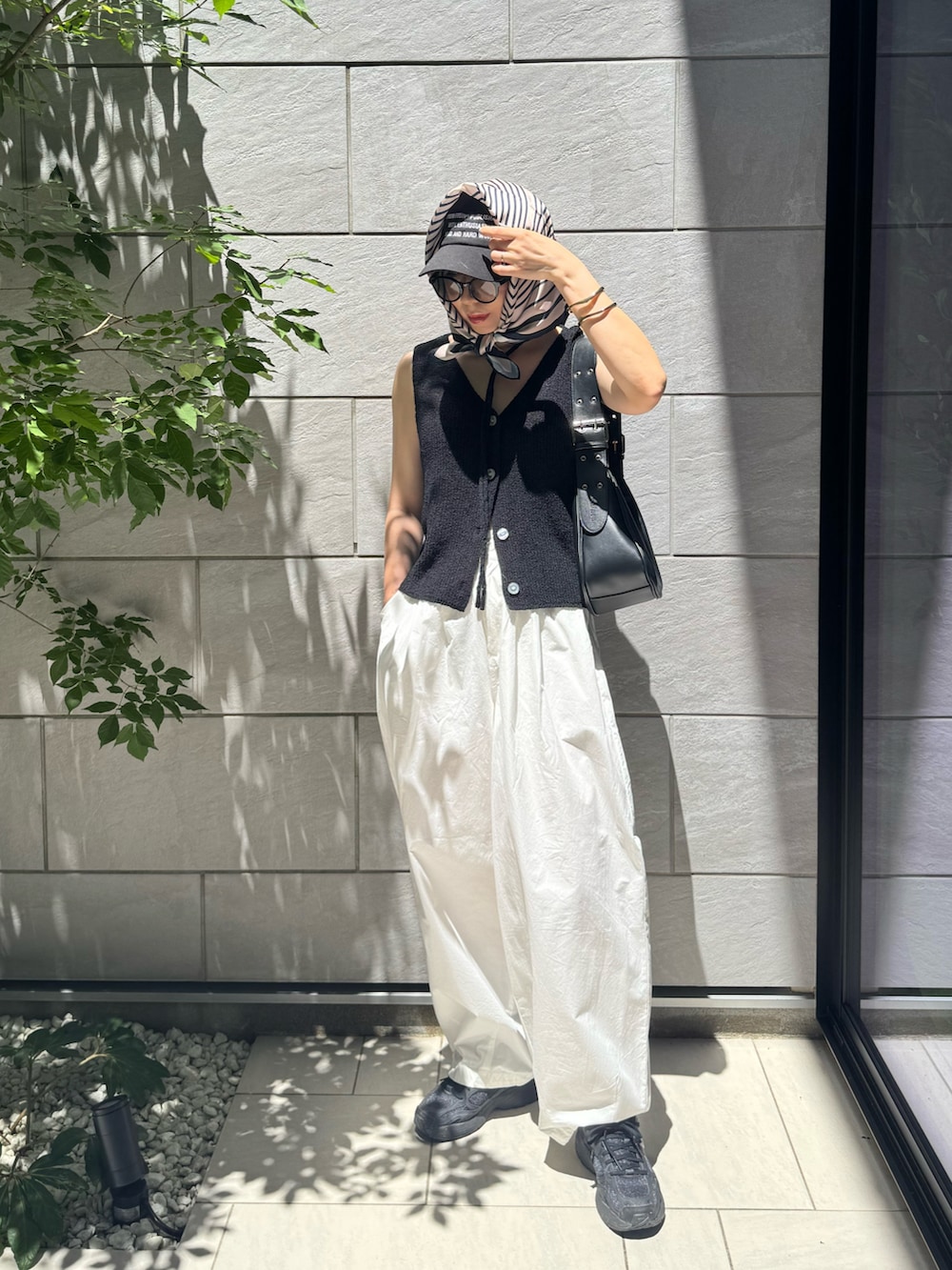 ブラック系のベスト、ブラック系のハンドバッグ、ホワイト系のその他パンツを着用したレディースの夏コーディネートの4枚目の写真