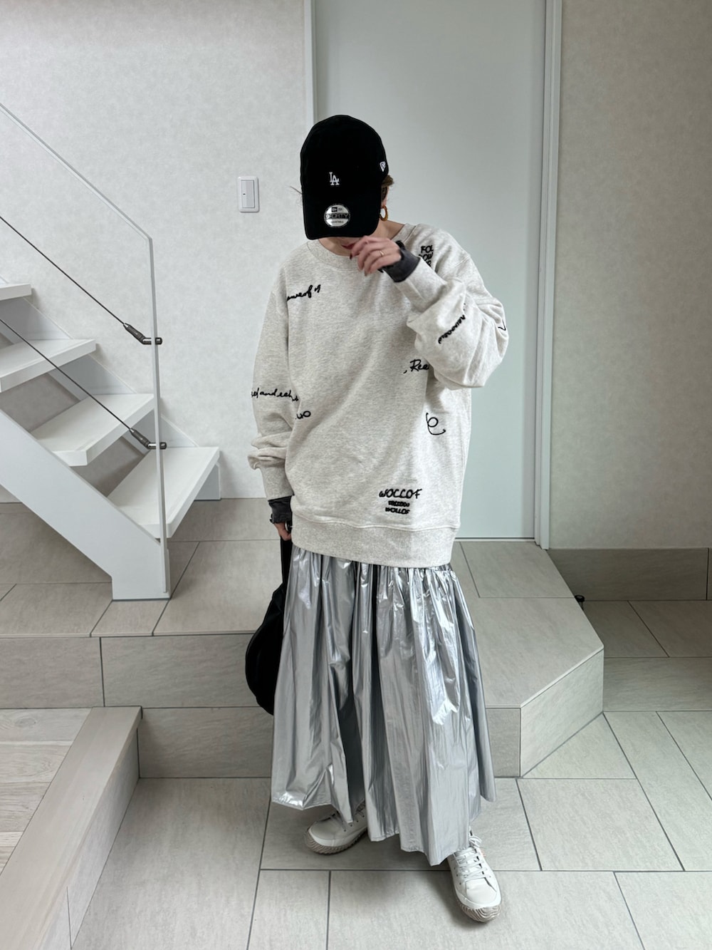 ホワイト系のスウェット、シルバー系のスカート、ブラック系のハンドバッグを着用したレディースの冬コーディネートの2枚目の写真