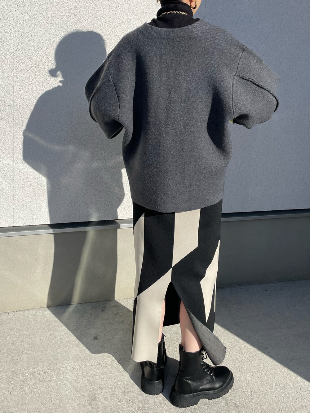 グレー系のノーカラーコート、ブラック系のブーツ、ブラック系のニット/セーターを着用したレディースの秋コーディネートの5枚目の写真