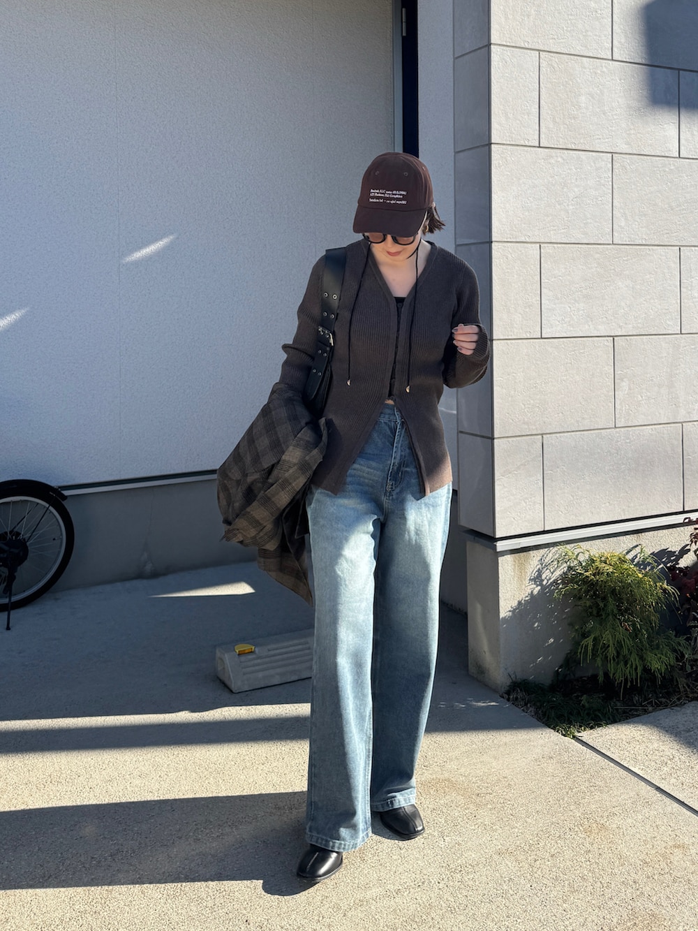ブルー系のデニムパンツ、ブラウン系のカーディガン/ボレロ、ブラック系のハンドバッグを着用したレディースの冬コーディネートの3枚目の写真