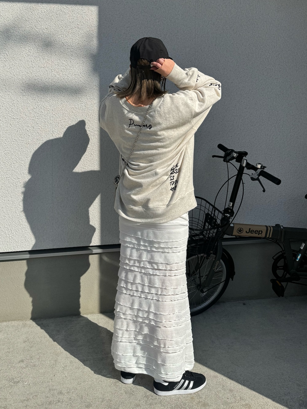 ホワイト系のスウェット、ホワイト系のスカート、ブラック系のスニーカーを着用したレディースの春コーディネートの4枚目の写真