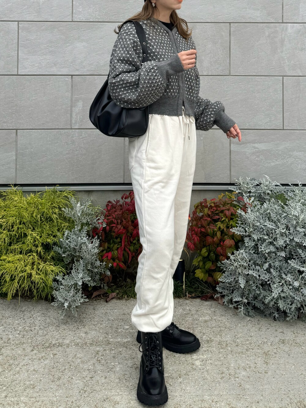 グレー系のニット/セーター、ブラック系のハンドバッグ、ブラック系のブーツを着用したレディースの秋コーディネートの3枚目の写真