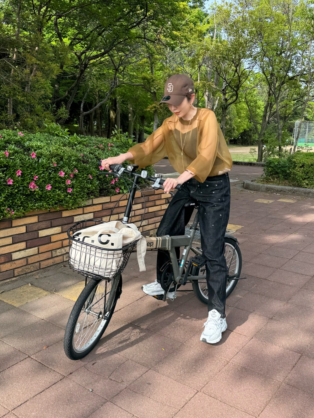 ブラック系のデニムパンツ、グレー系のスニーカー、ホワイト系のトートバッグを着用したレディースの春コーディネートの2枚目の写真