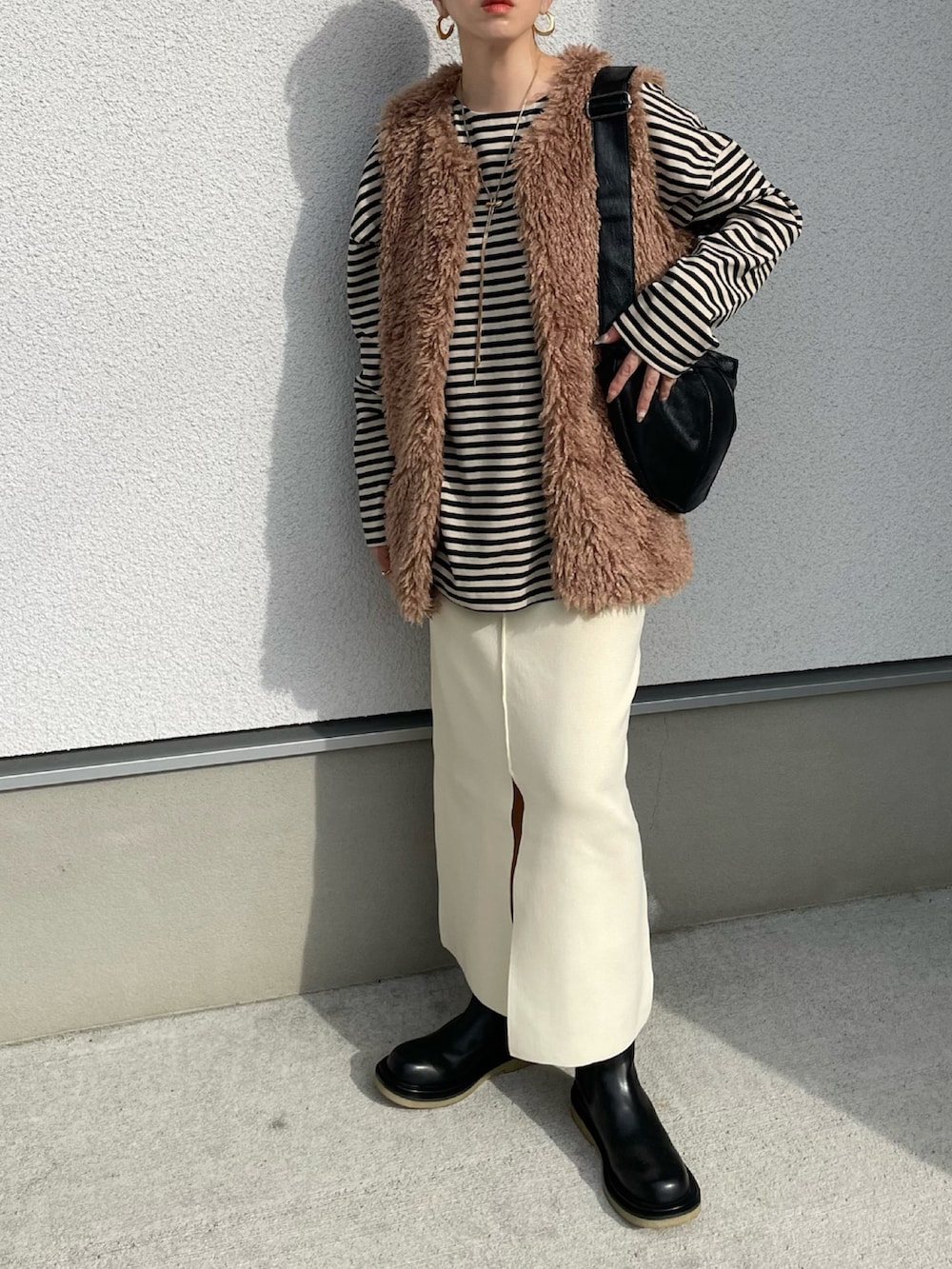 ホワイト系のスカート、ベージュ系のTシャツ/カットソー、ブラック系のブーツを着用したレディースの秋コーディネートの3枚目の写真