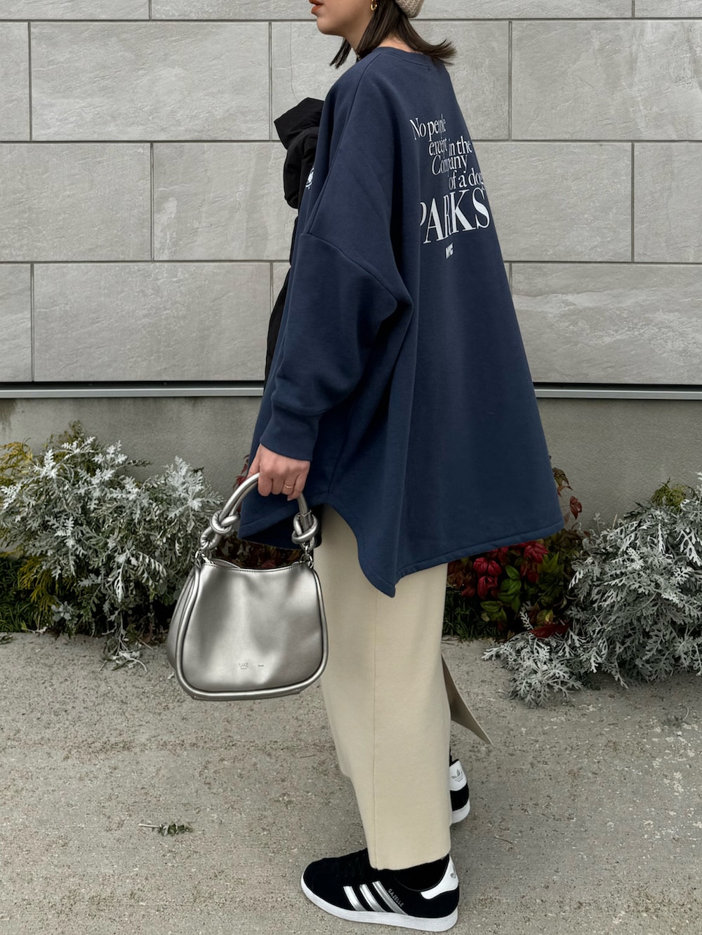 ブルー系のスウェット、シルバー系のショルダーバッグ、ブラック系のスニーカーを着用したレディースの冬コーディネートの2枚目の写真