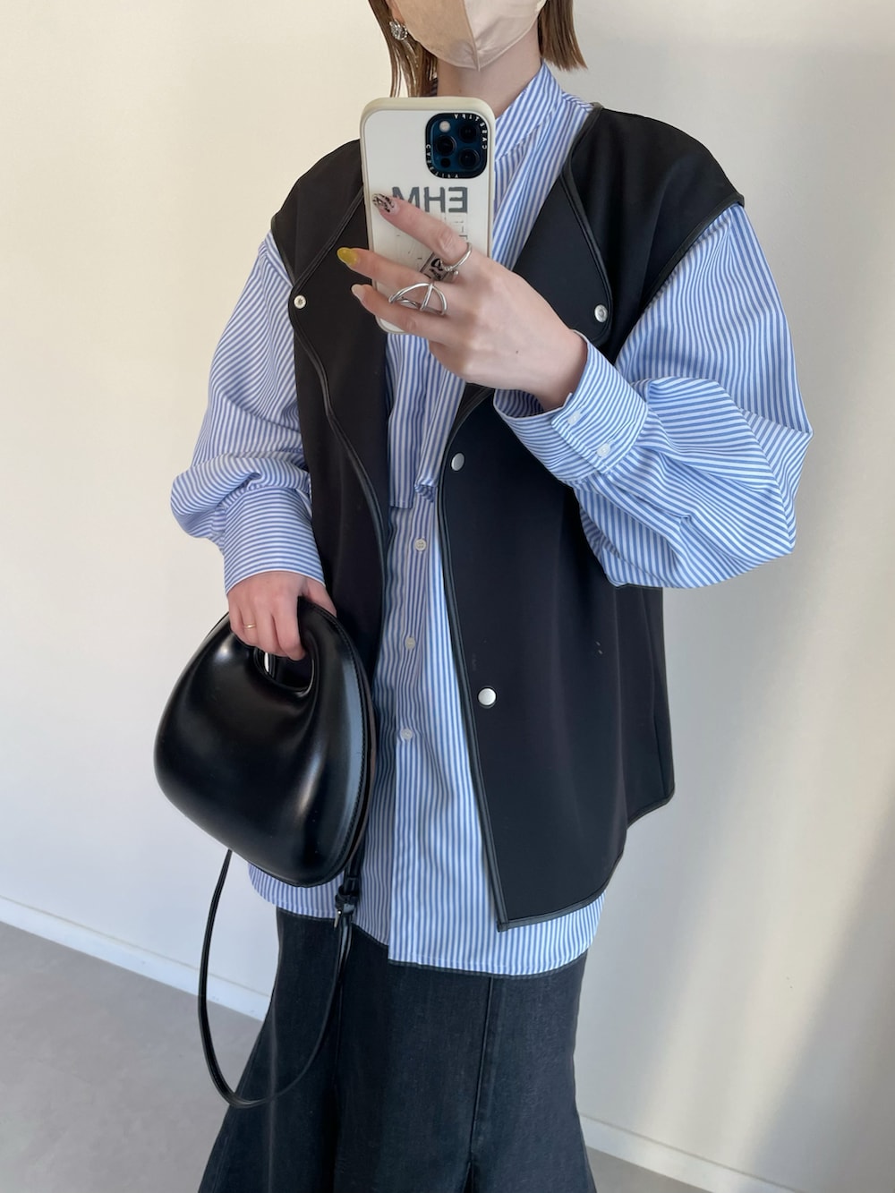 ブルー系のシャツ/ブラウス、ブラック系のベスト、ブラック系のスカートを着用したレディースの春コーディネートの3枚目の写真