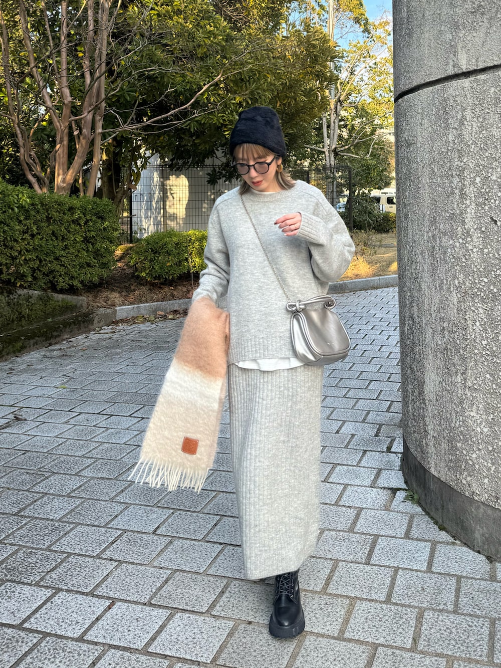 グレー系のワンピース、ブラック系のライダースジャケット、シルバー系のショルダーバッグを着用したレディースの冬コーディネートの4枚目の写真