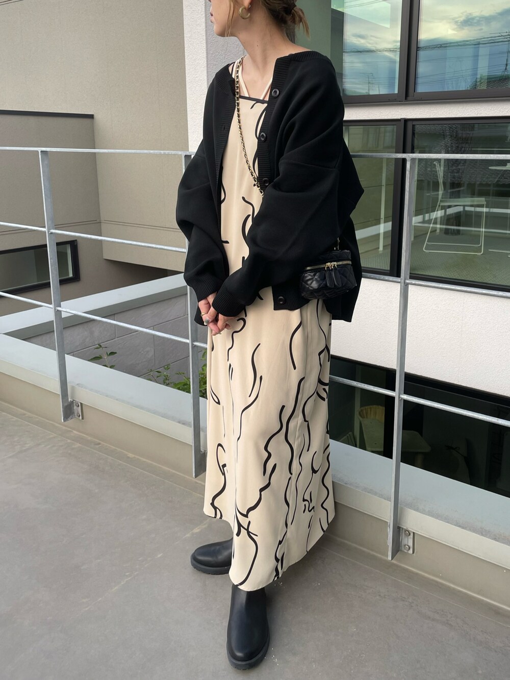 ブラック系のカーディガン/ボレロ、ホワイト系のワンピース、ブラック系のブーツを着用したレディースの秋コーディネートの4枚目の写真