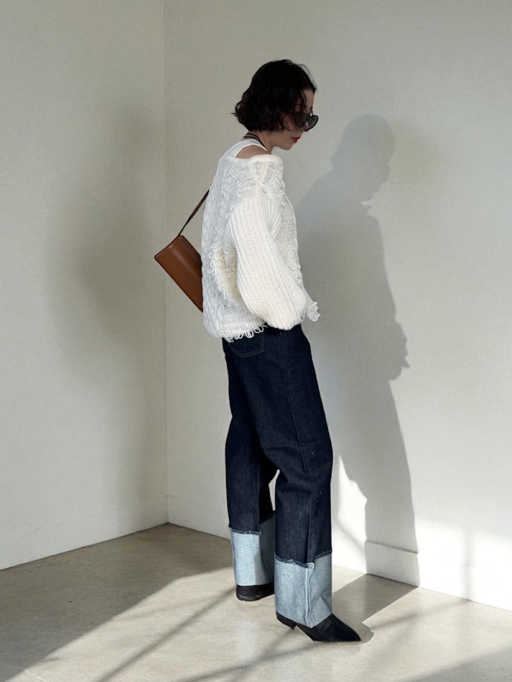 ブルー系のデニムパンツ、ベージュ系のショルダーバッグ、ホワイト系のニット/セーターを着用したレディースの秋コーディネートの4枚目の写真