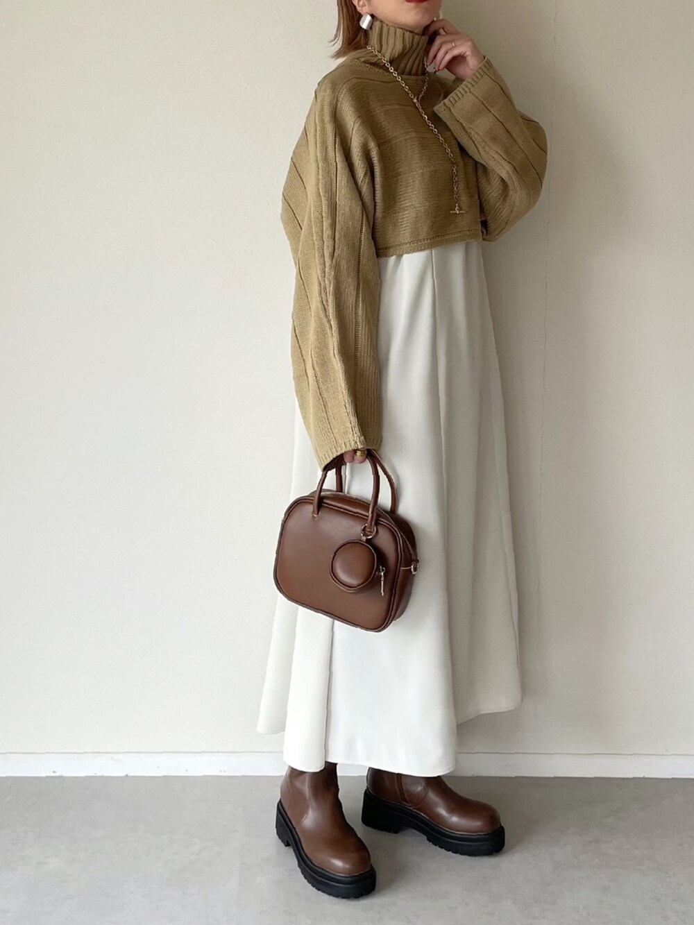 グリーン系のワンピース、ブラウン系のショルダーバッグ、ブラウン系のブーツを着用したレディースの秋コーディネートの2枚目の写真