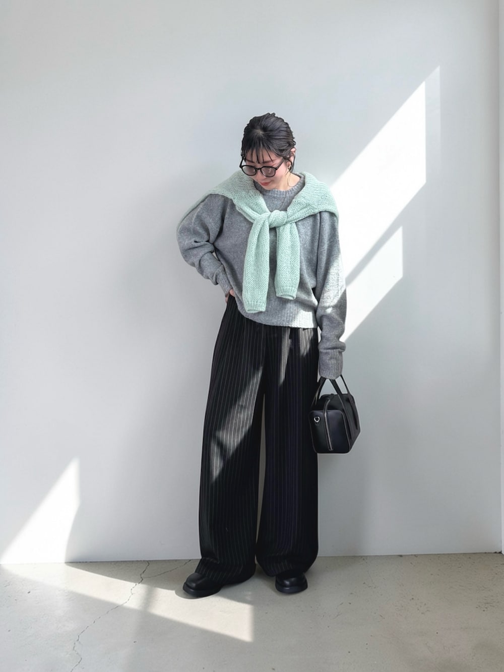 ブラック系のスラックス、ブラック系のその他シューズ、グリーン系のニット/セーターを着用したレディースの春コーディネートの2枚目の写真